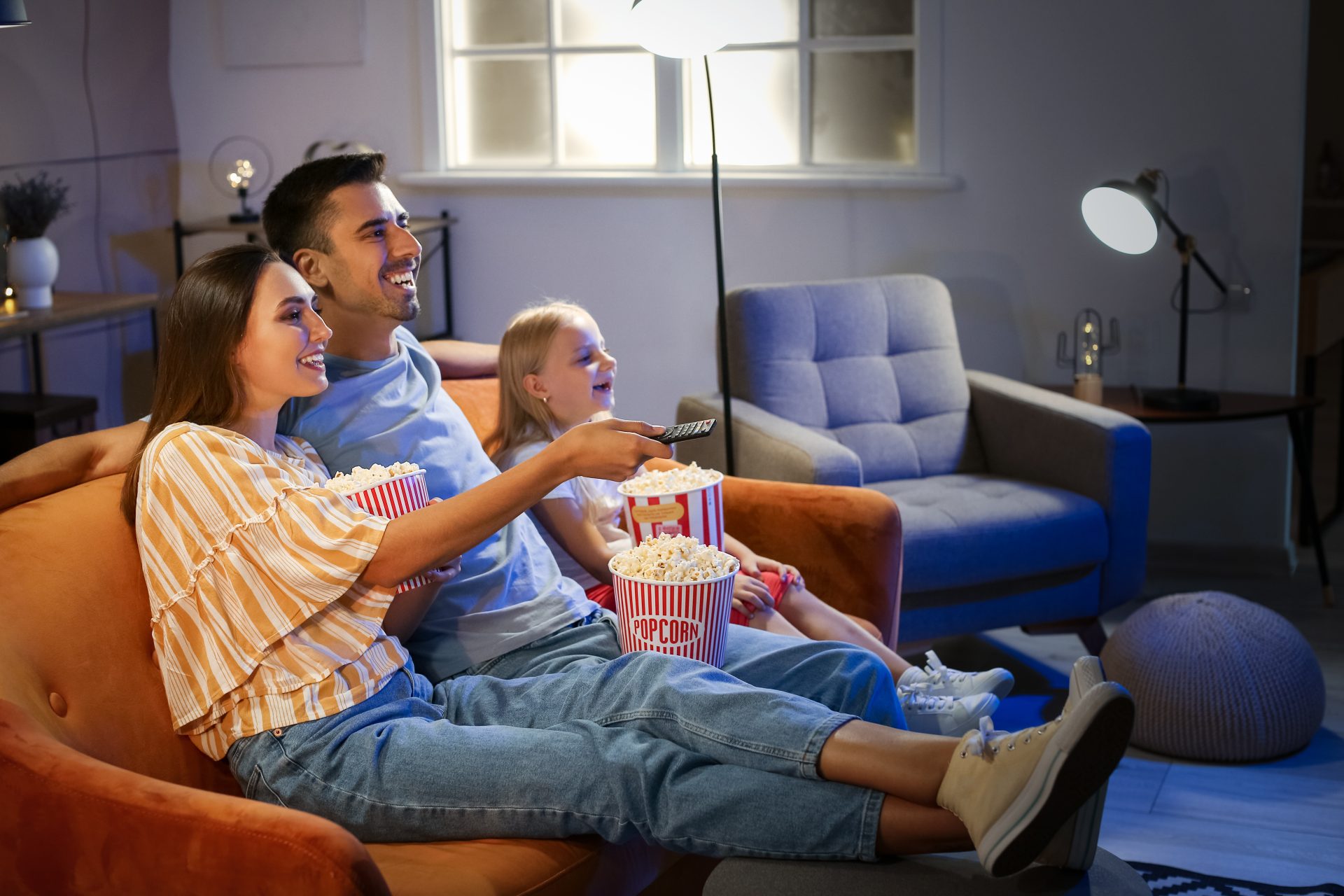 famille qui regarde un film avec du popcorn dans les mains